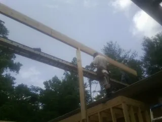 Carpenter setting a ridge beam over a new addition frame — Ice Dam Removal by Roofing Brothers in Wagener