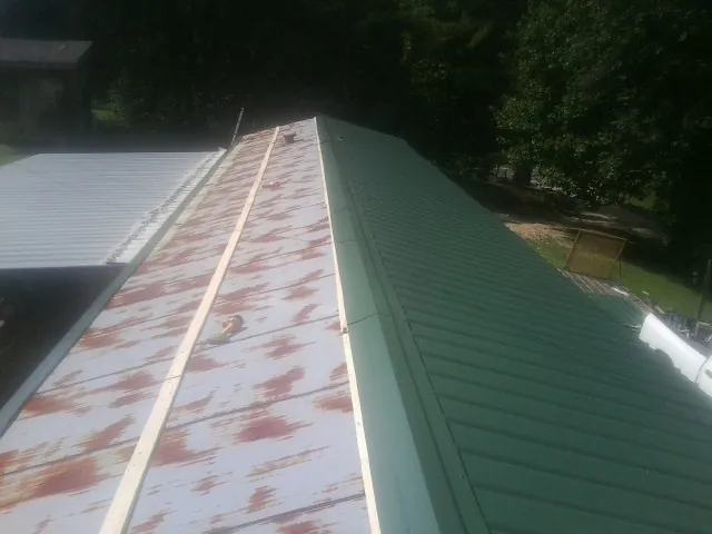Old rusted panels beside newly installed green metal roofing — Wind Damage Roof Repair by Roofing Brothers in Wagener