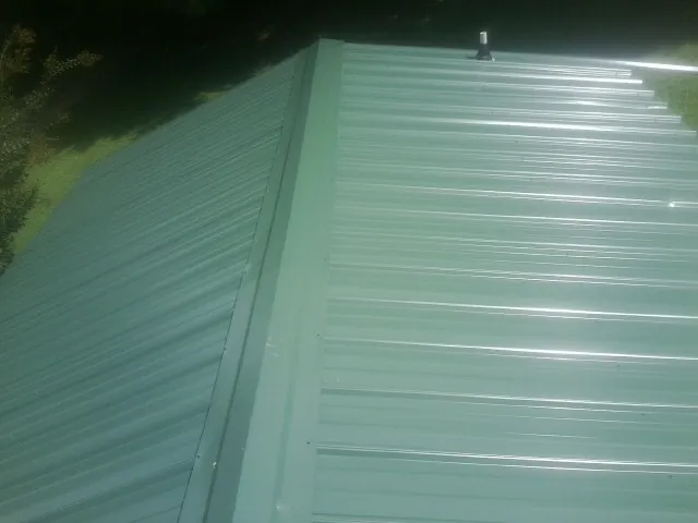 New green metal panels meeting at the ridge of a roof — Flat Roof Repair work by our crew in Wagener