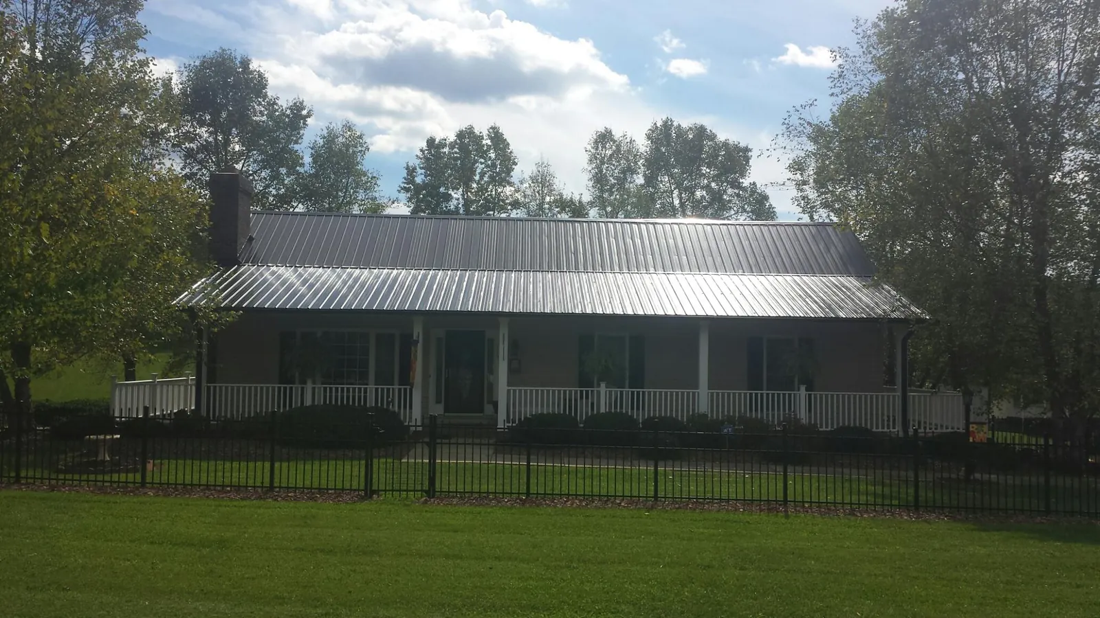 Gray metal roof on a brick ranch with a full width front porch — Gutter Guard Installation work by our crew in Wagener