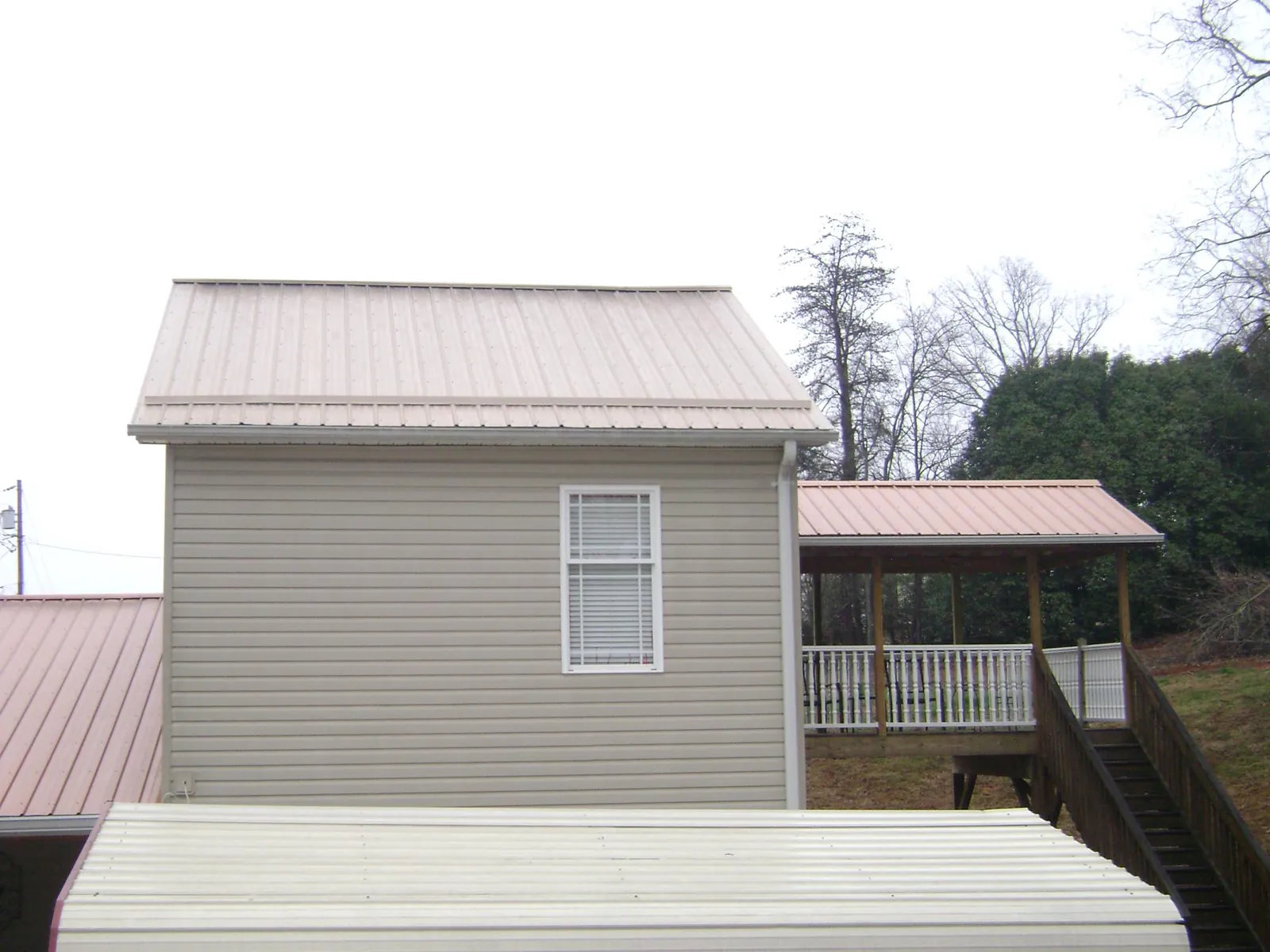 Tan metal roofs on a two story addition and attached porch, from a Roof Replacement job in Wagener
