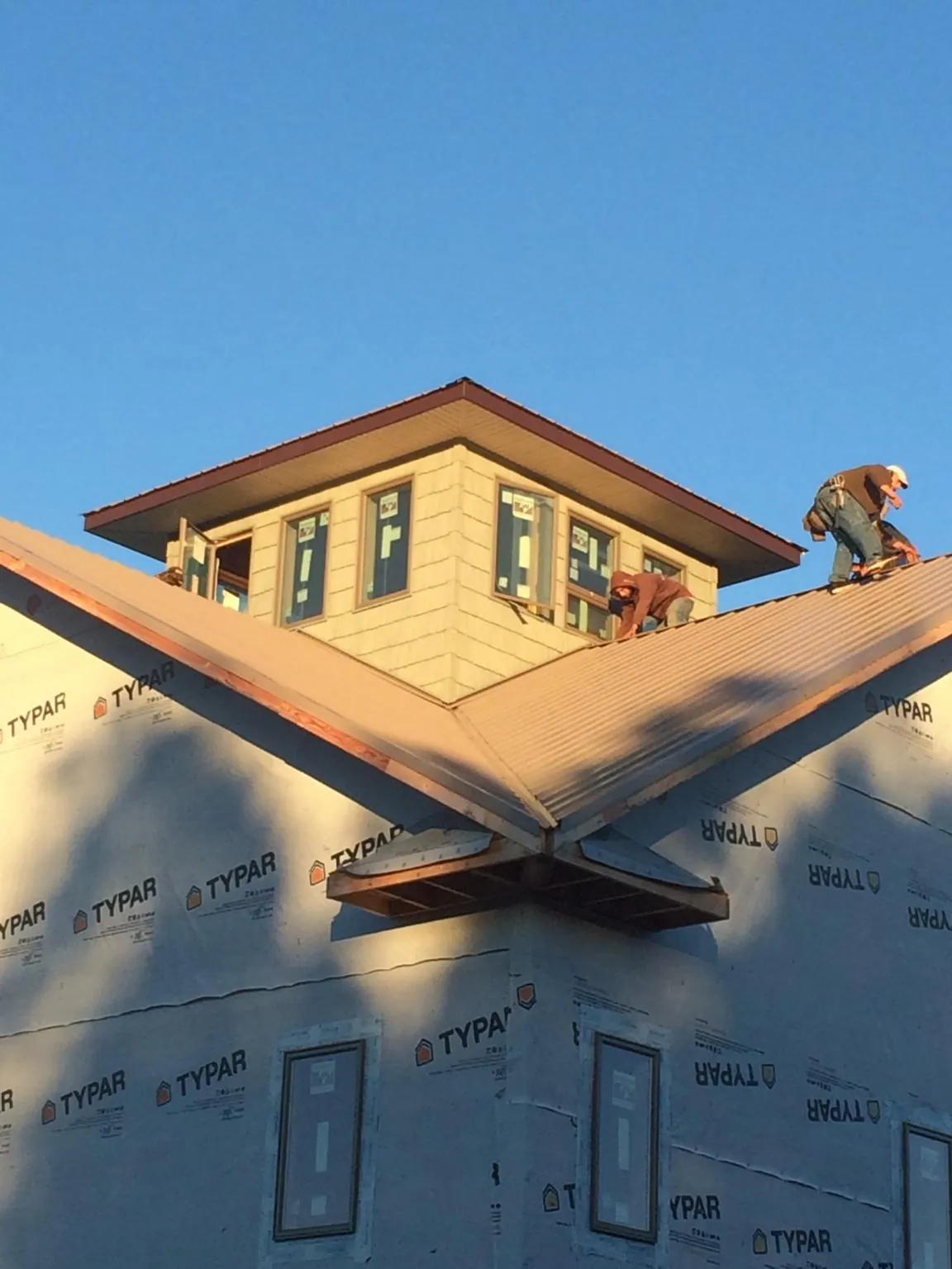 Roofers working around a rooftop cupola on a new metal roof at sunset — Roof Waterproofing in Wagener by Roofing Brothers